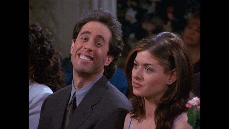 Jerry Seinfeld mugging after discovering his new girlfriend, Beth (Debra Messing), is a horrible racist, while she sits stonefaced staring straight ahead.