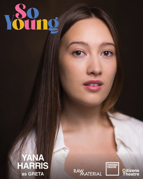  Young woman (Yana Harris) with long brown hair and white top posing against a solid dark background.