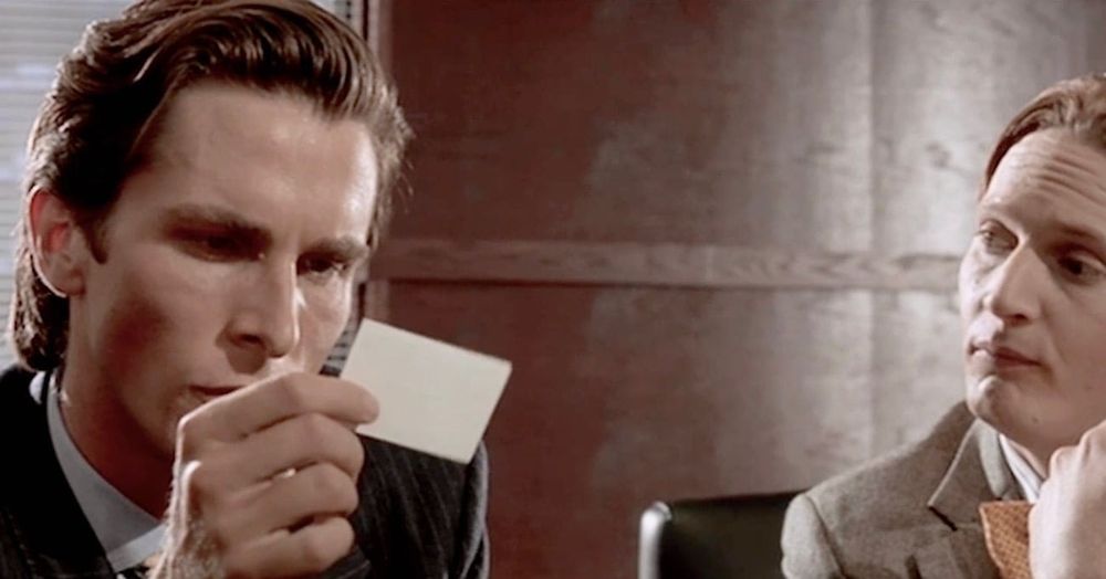 Photo of actor a Christian Bale as Patrick Bateman in American Psycho. Bateman is enviously admiring a colleague's business card