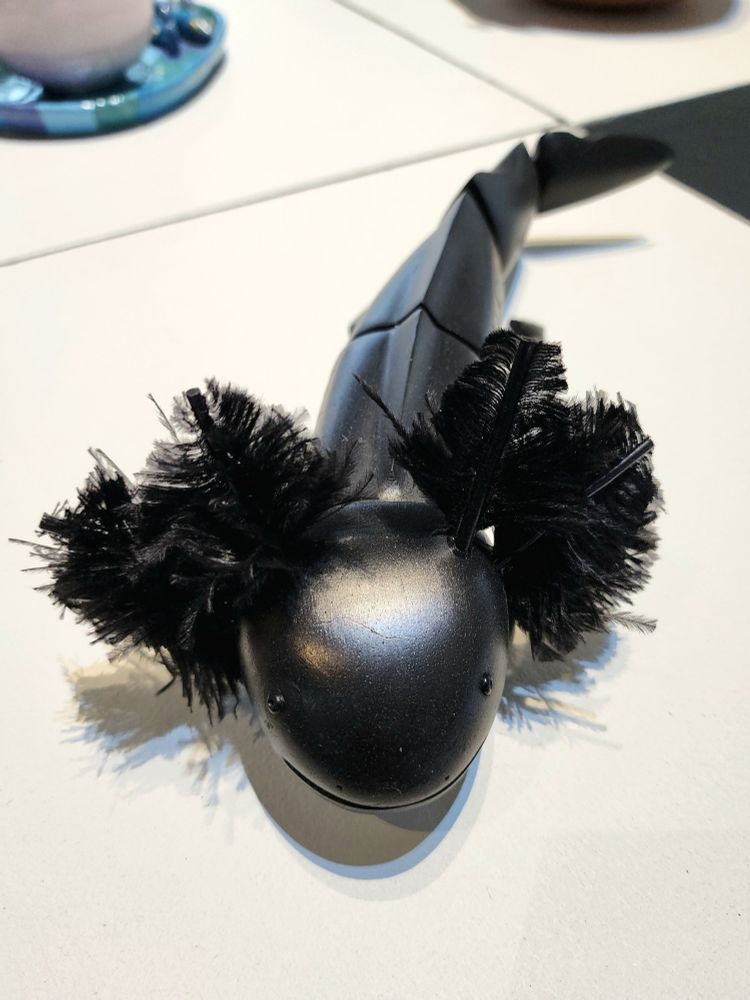 Artisanal black axolotl figurine with black feathers instead of gills.