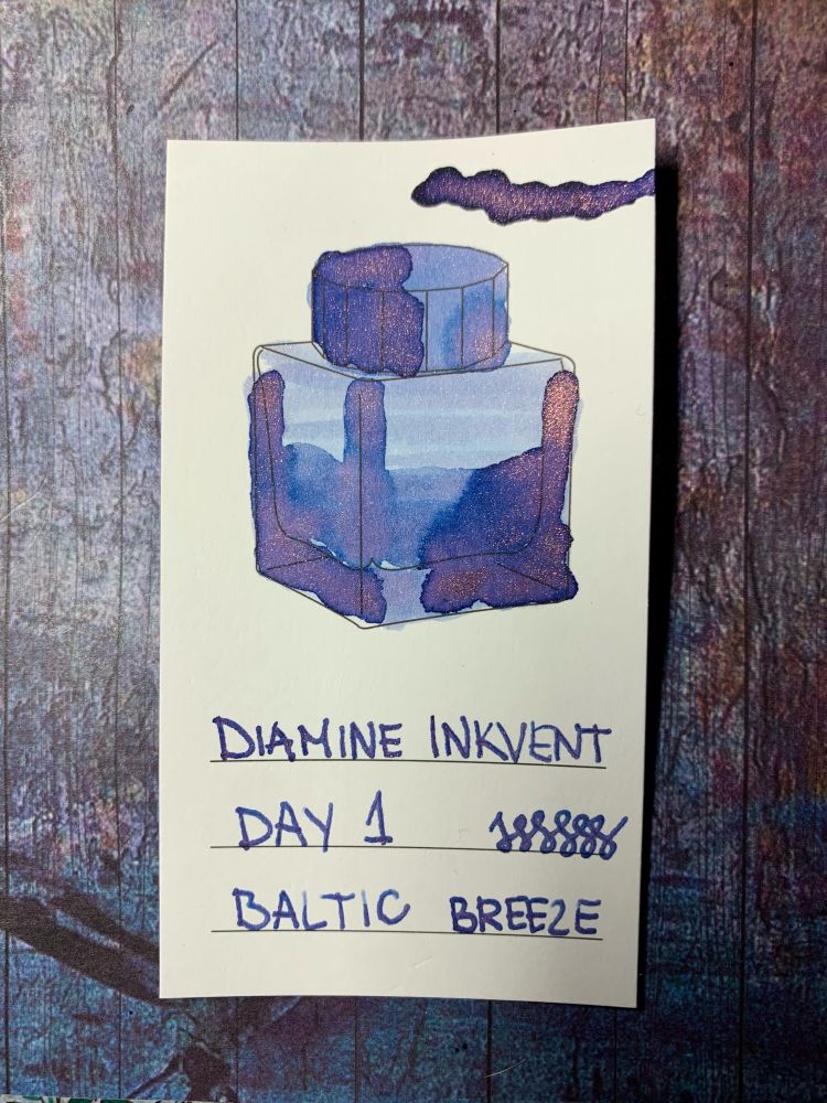 A swatch of Diamine Inkvent Day 1 fountain pen ink, Baltic Breeze. The ink is a light blue with pinkish/light coppery sheen.