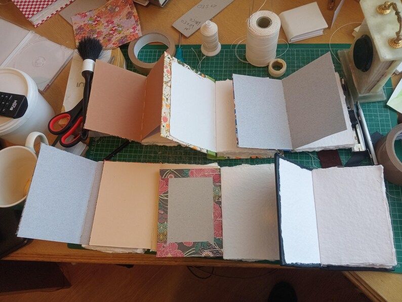 Seven opened books, showing the endpapers of inside of the front cover.