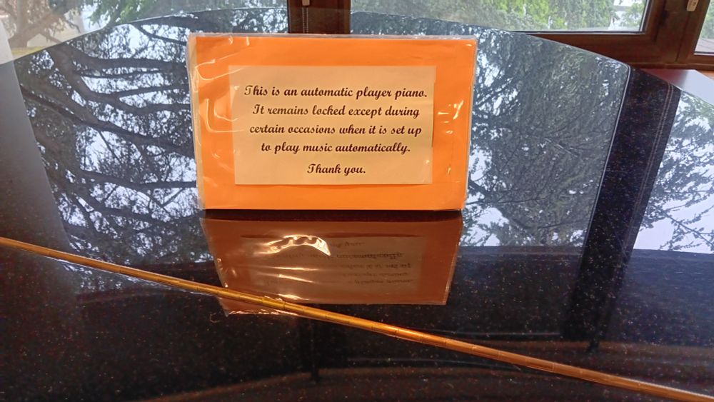 Sign on top of piano: "This is an automatic player piano. It remains locked except during certain occasions when it is set up to play music automatically. Thank you."