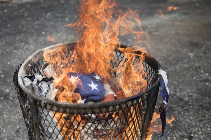 burning American flag in a trash can