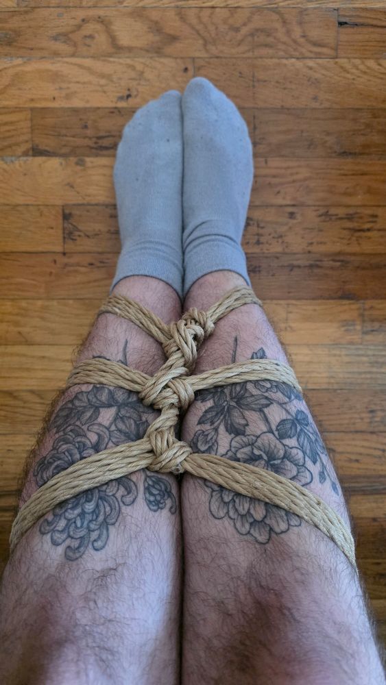 My legs in a calfbiner tie, with visible tattoos and socks on