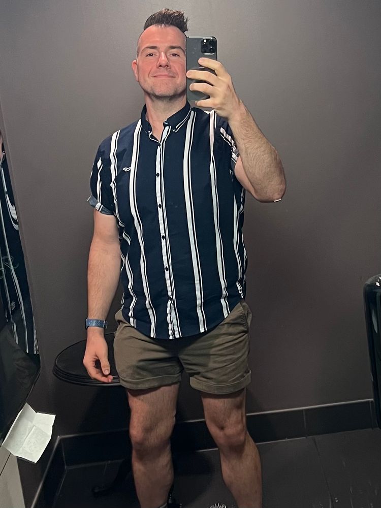 Bathroom mirror selfie wearing a striped button up and lil shorts 