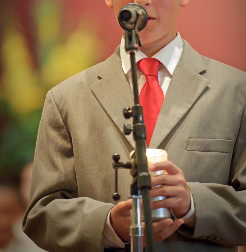 A youth takes his turn reciting a passage and teaching at the I Confirm Service, holding a candle to keep his hands steady.