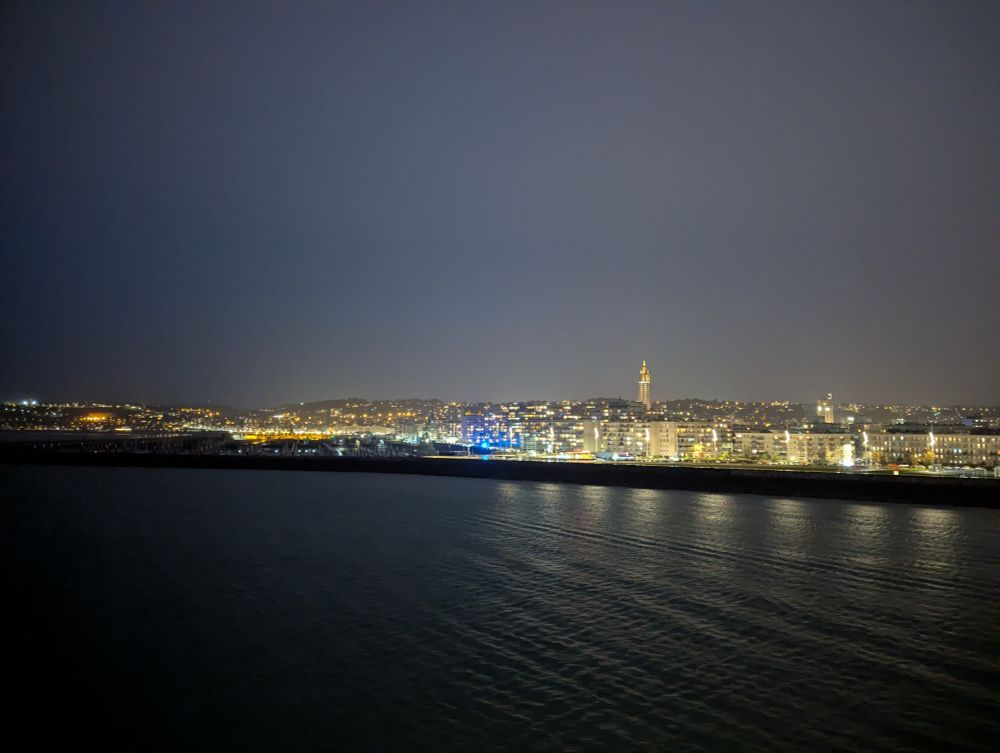 Hafen und Stadtbild vom Wasser aus gesehen. Die hereinbrechende Nacht stellt fuw Lichter der Stadt heraus. 