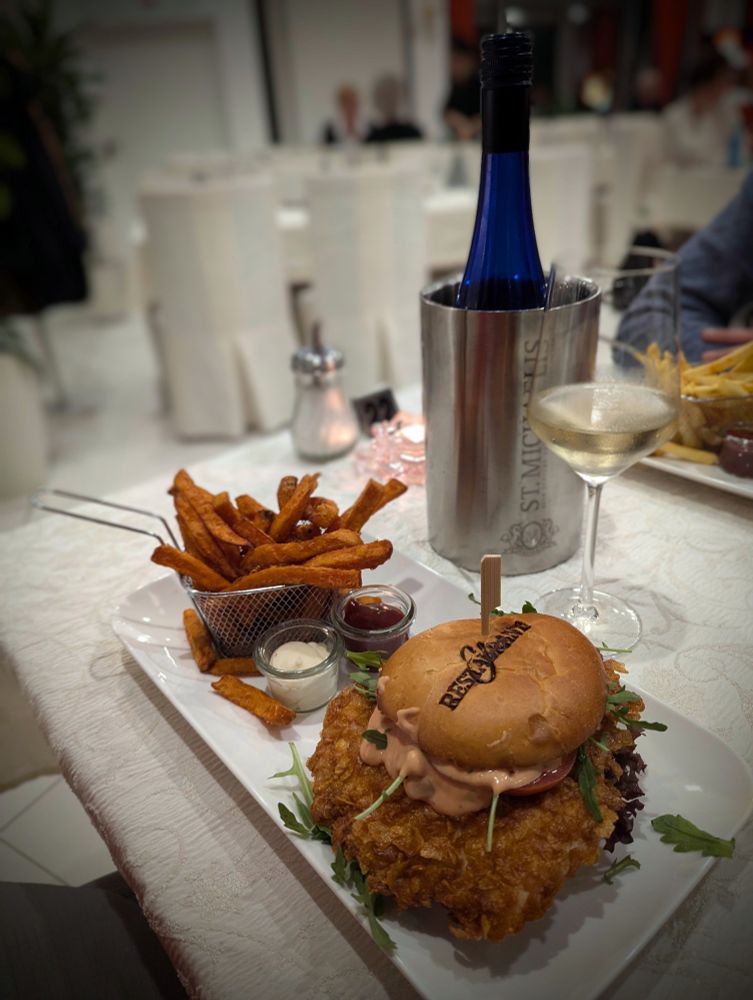 Bürger mit crispy Chicken und Pommes. Dazu ein Glas Weißwein im Restaurant.