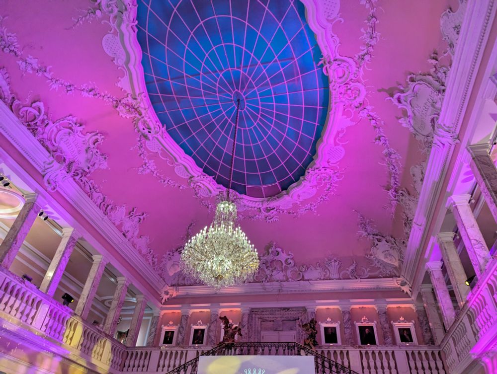 Grundton Pink. Abgebildet sind die Treppen und die umlaufende Balustrade. Die rech verzierte Decke hat einen ovalen Glaseinsatz.