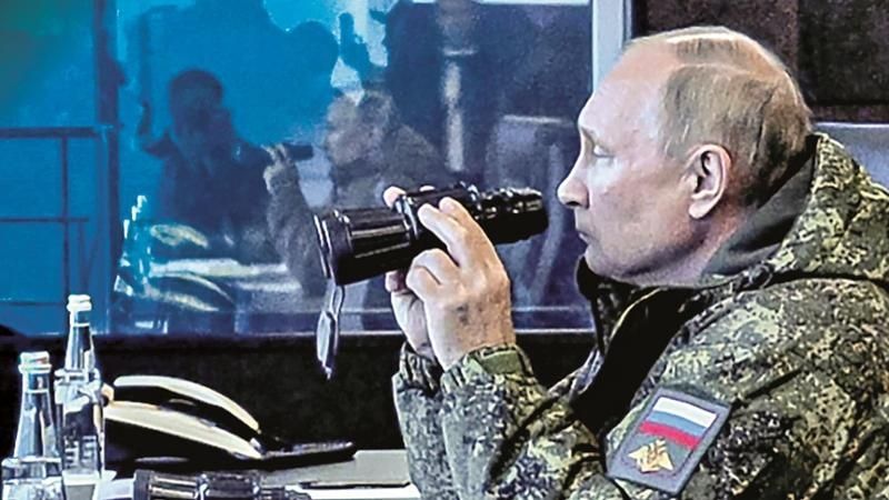 Putin vestito da militare guarda in un cannocchiale.
