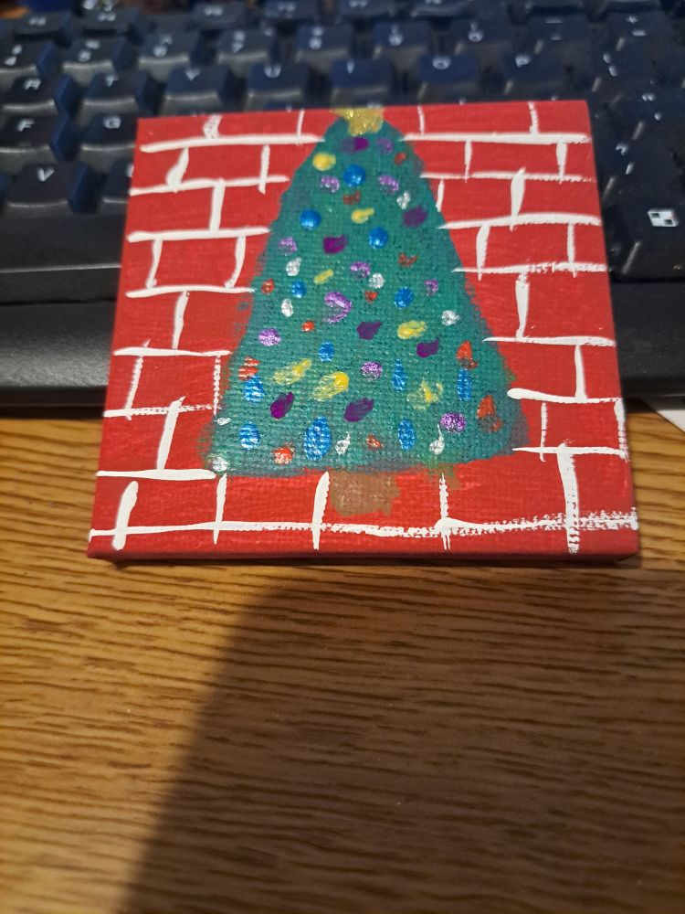 A decorated Christmas tree on a red brick background. 
