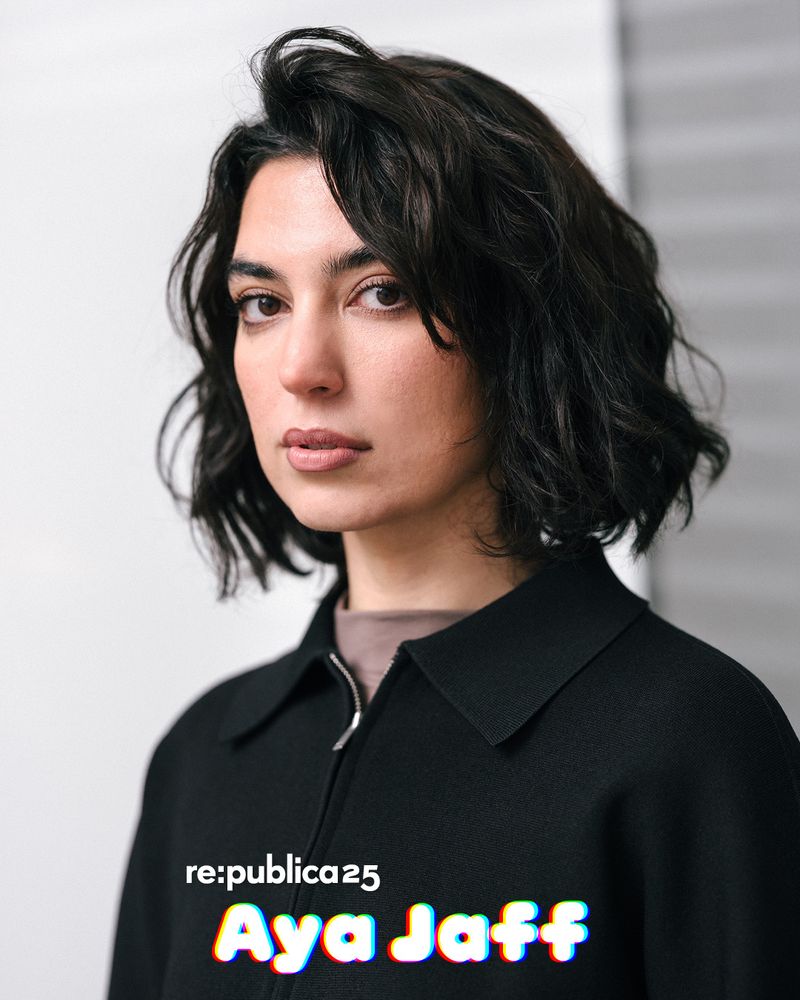 Foto von Aya Jaff. Sie hat kinnlange Haare und blickt seitlich in die Kamera. Sie trägt einen dunklen Pullover.