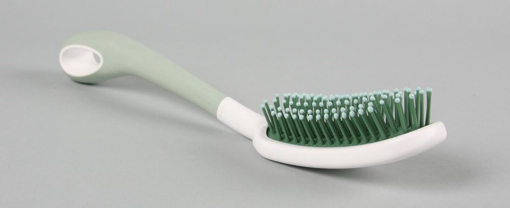 A long handled hairbrush with green coloured thick bristles.