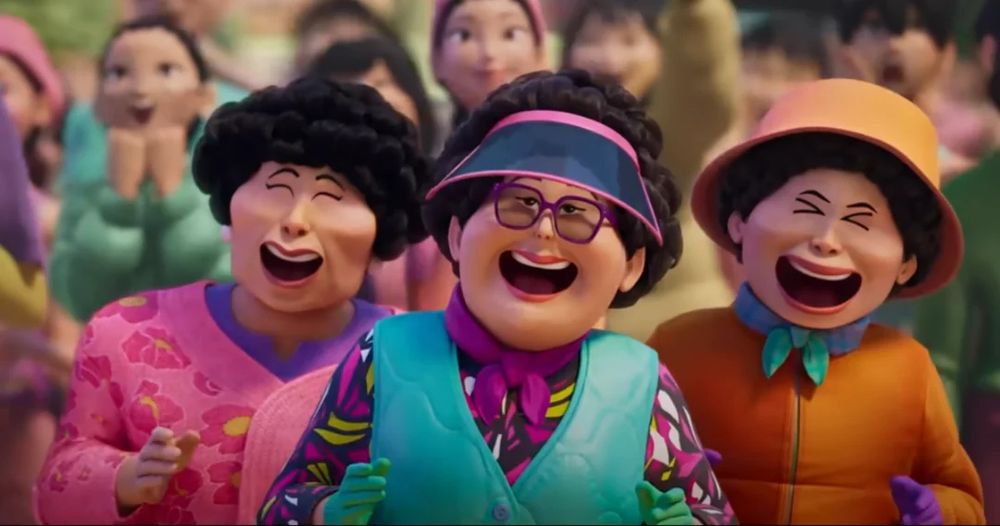 The three aunties in their visors and vests and colourful sweaters from KPop Demon Hunters. They are smiling, having a great time at the Saja Boys outdoor concert.