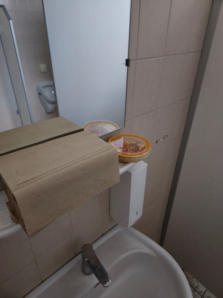 Une boîte de houmous près du lavabo des toilettes d'entreprise