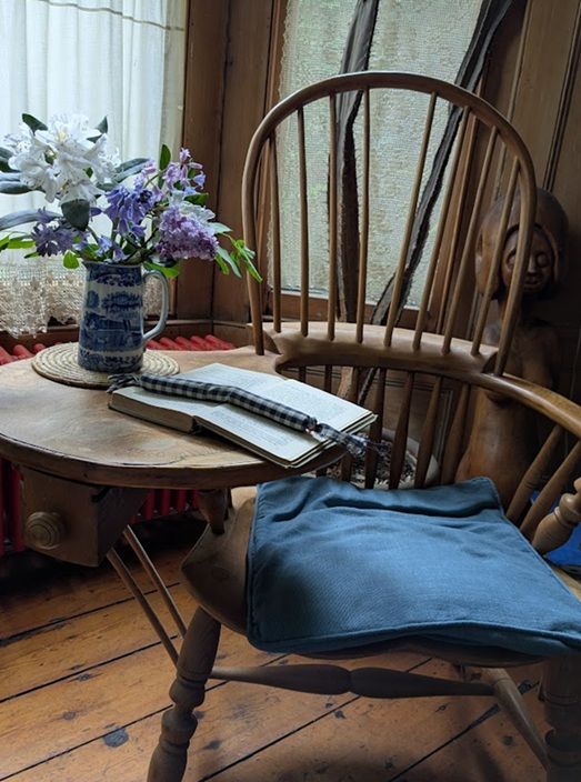Old handmade chair with reading table, book and flowers from the home of writer Joan Aiken