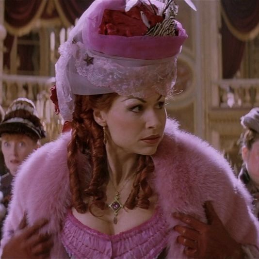 a screenshot from 2004's "The Phantom of the Opera" movie adaptation, with Minnie Driver playing the role of Carlotta, dressed in a hideous (therefore gorgeous) pink ensemble. She is the diva of the opera house.