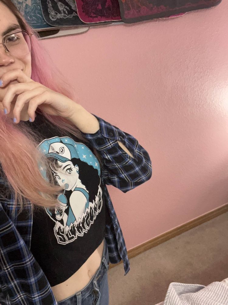 Photo of a woman with pink hair in a cropped top and a flannel