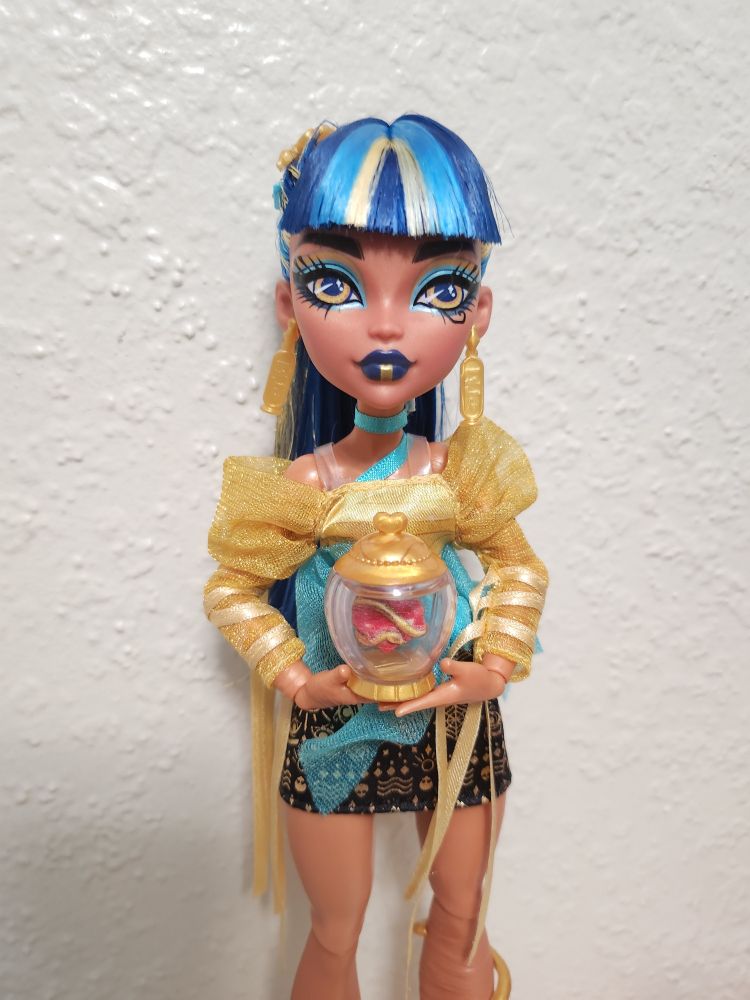 Core Refresh Cleo De Nile stands in front of a white wall, holding her heart in a jar accessory.