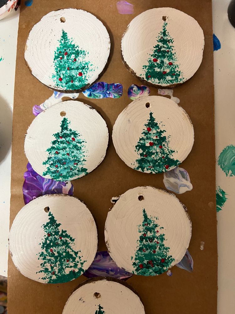 A set of round wooden ornaments containing Christmas trees. 