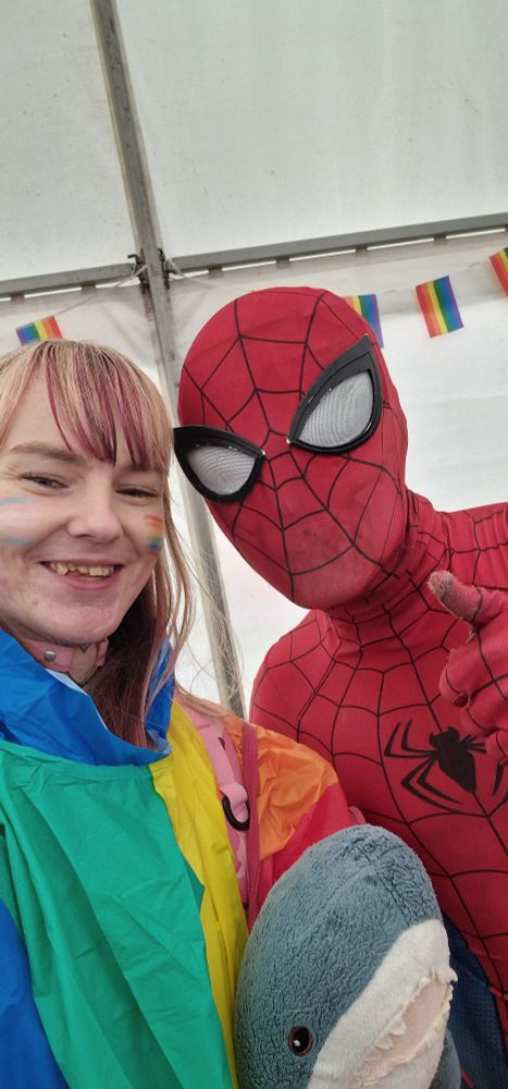Another photo of me, this time wearing a rainbow rain poncho, posing with Spiderman (he's the real Spiderman). Spidey is pointing at the camera looking cool. Finlay is in the middle being a poser.