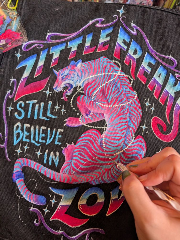 A progress shot of me painting the back panel of my Freaks jacket. I'm using a nail art dotter to apply pearls to strings wrapped around a hot pink tiger monster.