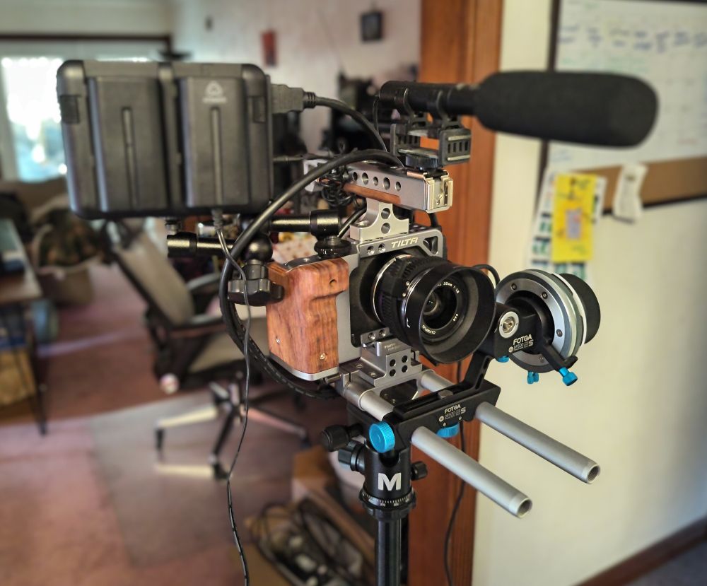 A blackmagic pocket cinema camera rig, consisting of the camera, a follow focus system, a microphone, a wood furniture cage for the camera, and an external recording system.