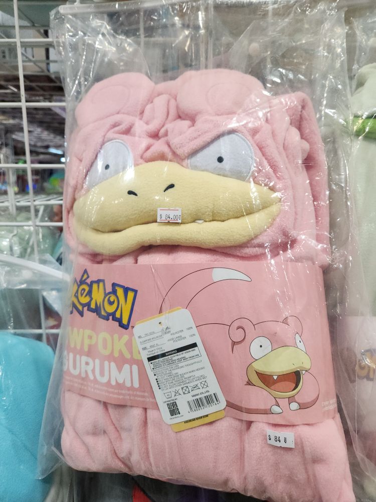A Slowpoke kigurumi still in packaging. The fabric is folded over Slowpoke's eyes a bit, which makes it look like it's frowning.