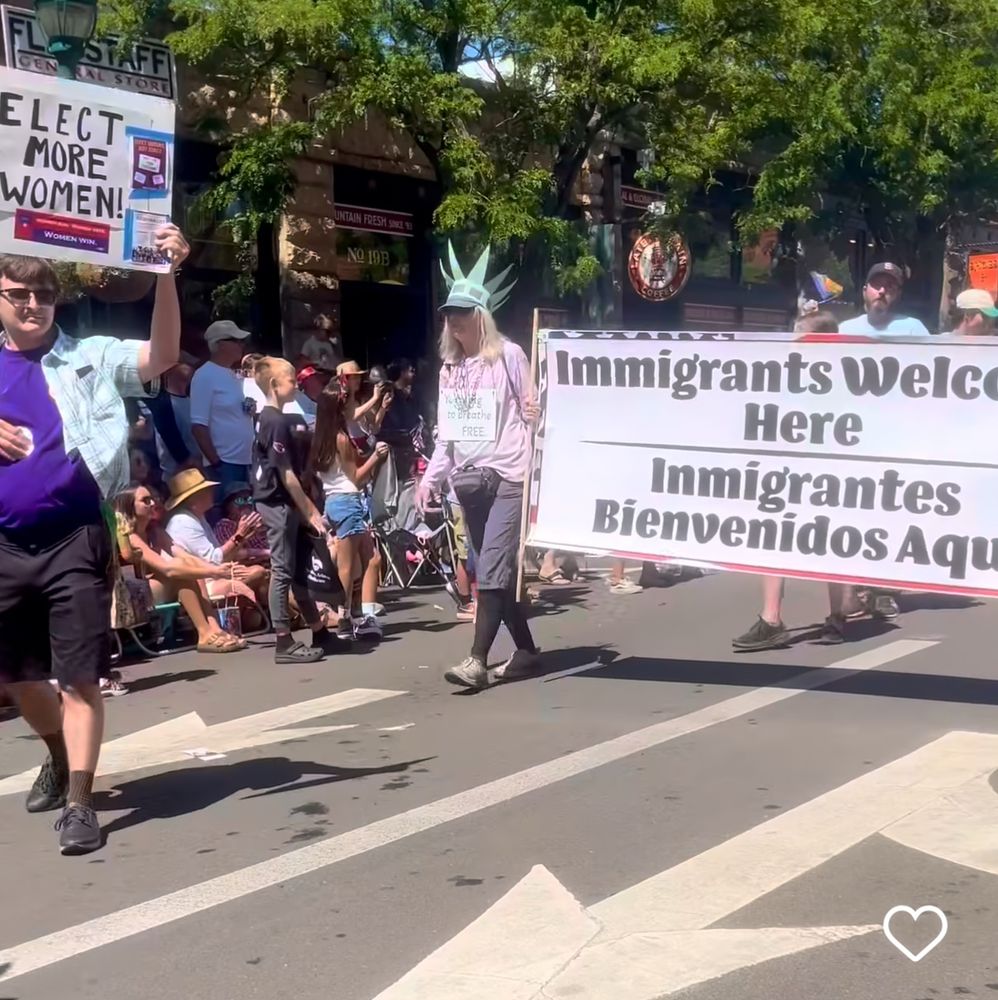 A banner carried at a parade that says Immigrants Welcome Here.