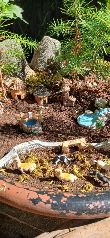 Miniature village with animal pen amid Penjing of young Douglas fir trees.