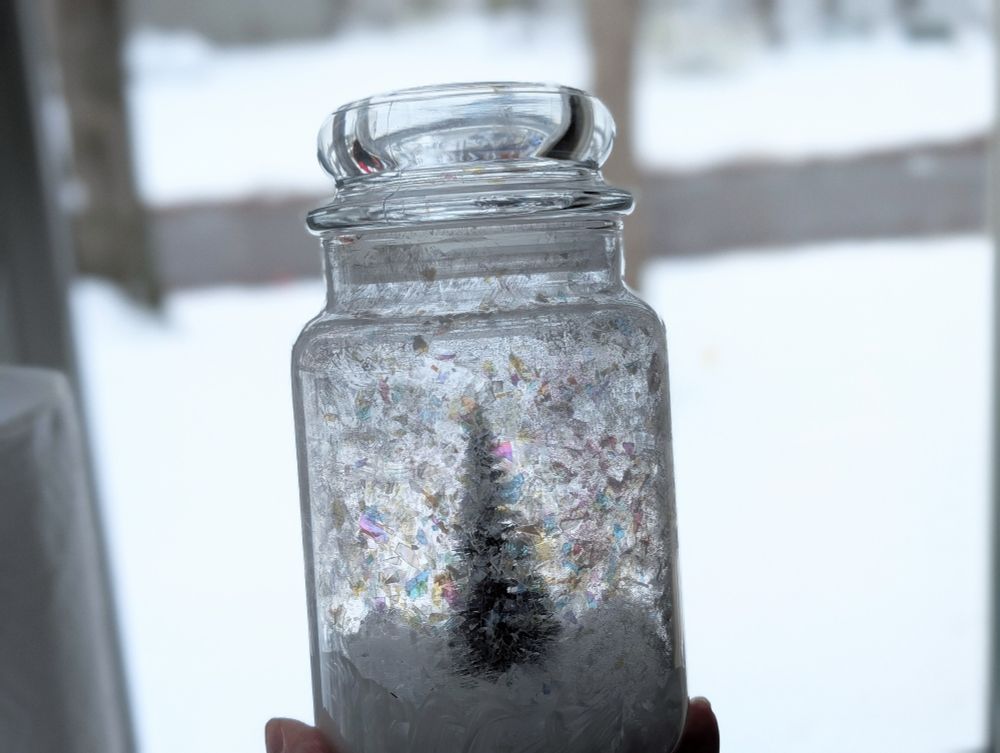 Snow globe/terrarium sort of thing made from an old candle jar, the dregs of iridescent melamine snow, fiberfill, glitter, mod podge and a tiny tree. Adding string of tiny battery lights I'll affix to the inside lid. 