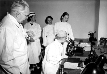 First from the left: Professor Józef Laskowski, On the microscope  the Queen of Belgium and above doctor
Ludwika Sikorowa and doctor Maria Dąbska 