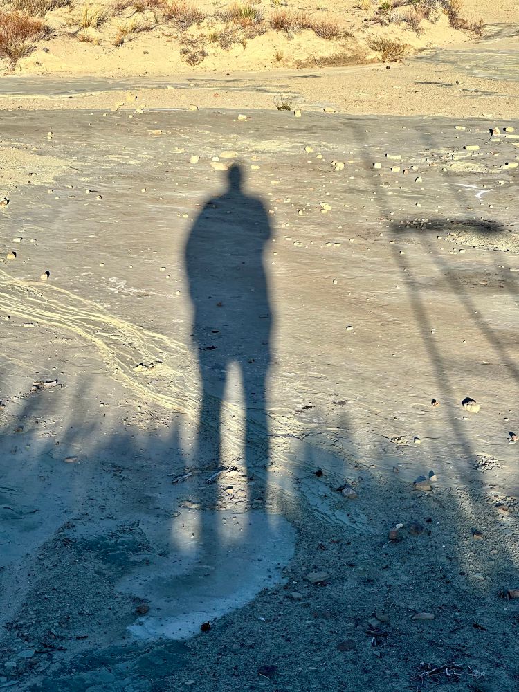 My shadow on the pale alkali soil of a dry wash in the Great Basin. 