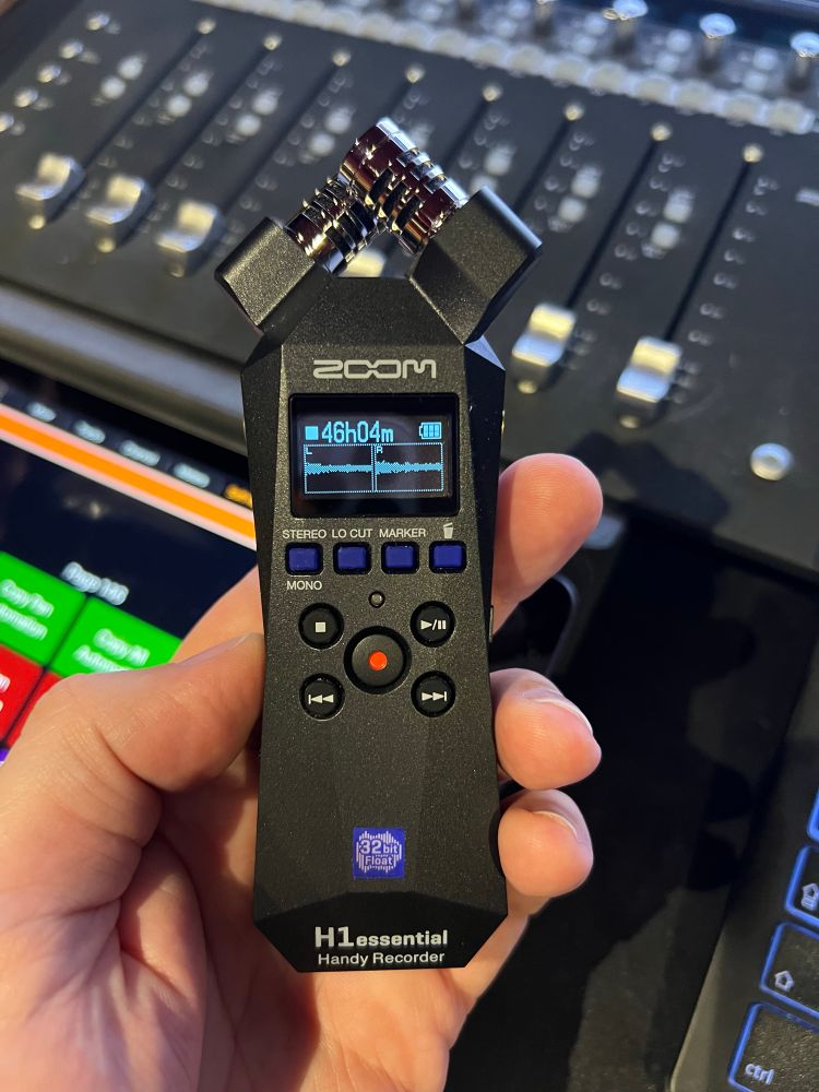 Closeup picture of a Zoom H1 essential portable recorder being held in one hand.
