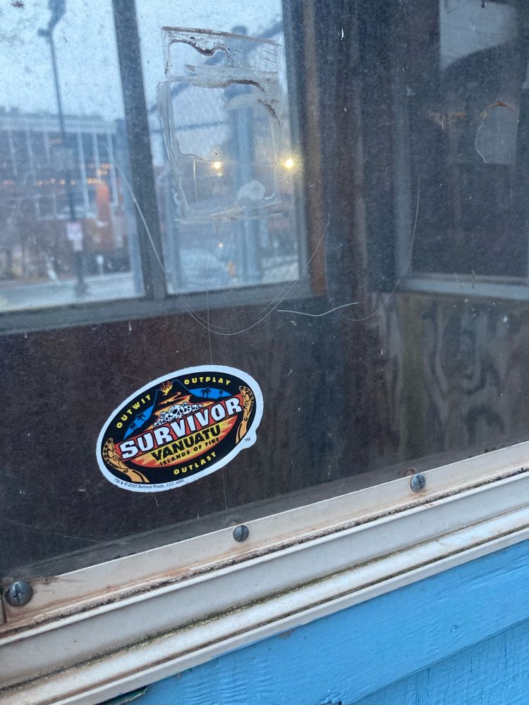 A sticker showing the Survivor Vanuatu logo on a random phone booth