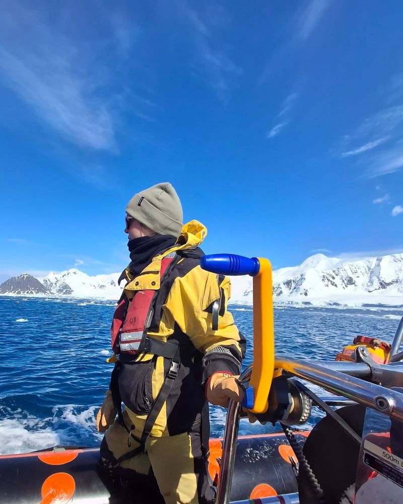 A member of our team in a boat, on a polar fieldtrip, wearing yellow waterproofs and a lifejacket