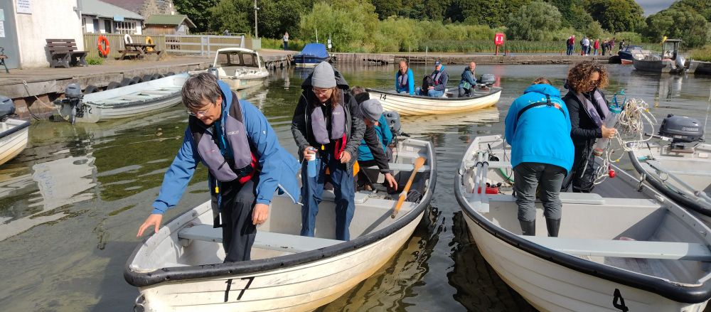 A group of people, wearing lifejackets, in rowing boats