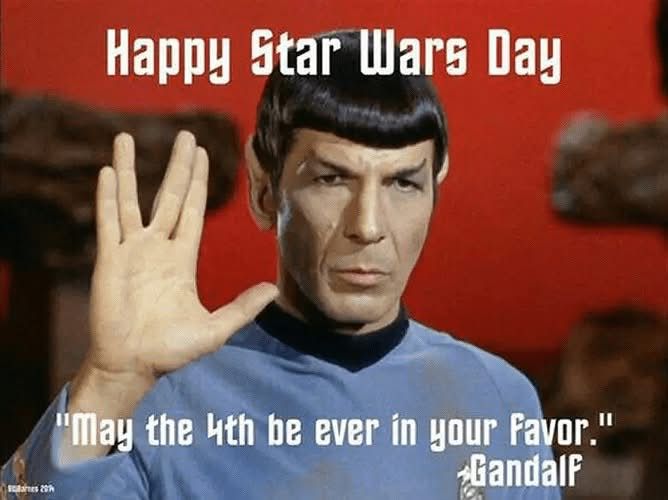 A humorous meme featuring the character Spock from Star Trek, holding up the Vulcan salute. The image text reads: ‘Happy Star Wars Day’ and ‘May the 4th be ever in your favor.’ – Gandalf. The quote mixes elements from Star Wars, The Hunger Games, Star Trek, and The Lord of the Rings for comedic effect.
