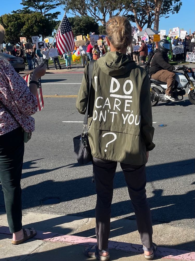 Woman in jacket like the one Melania Trump wore to visit victims of a flood only this one reads “ I DO care, Don’t YOU?”