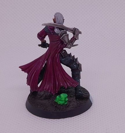 Fantasy elf wielding two short swords in black pants, purple coat and white hair, with green crystals on the base. Pictured from the back.