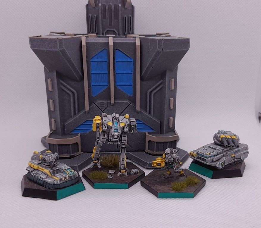 J.Edgar Hovercraft, Gun omnimech, Amazon battle armor, Pike support vehicle left to right, all in grey and yellow paintscheme in front of a dark grey building.