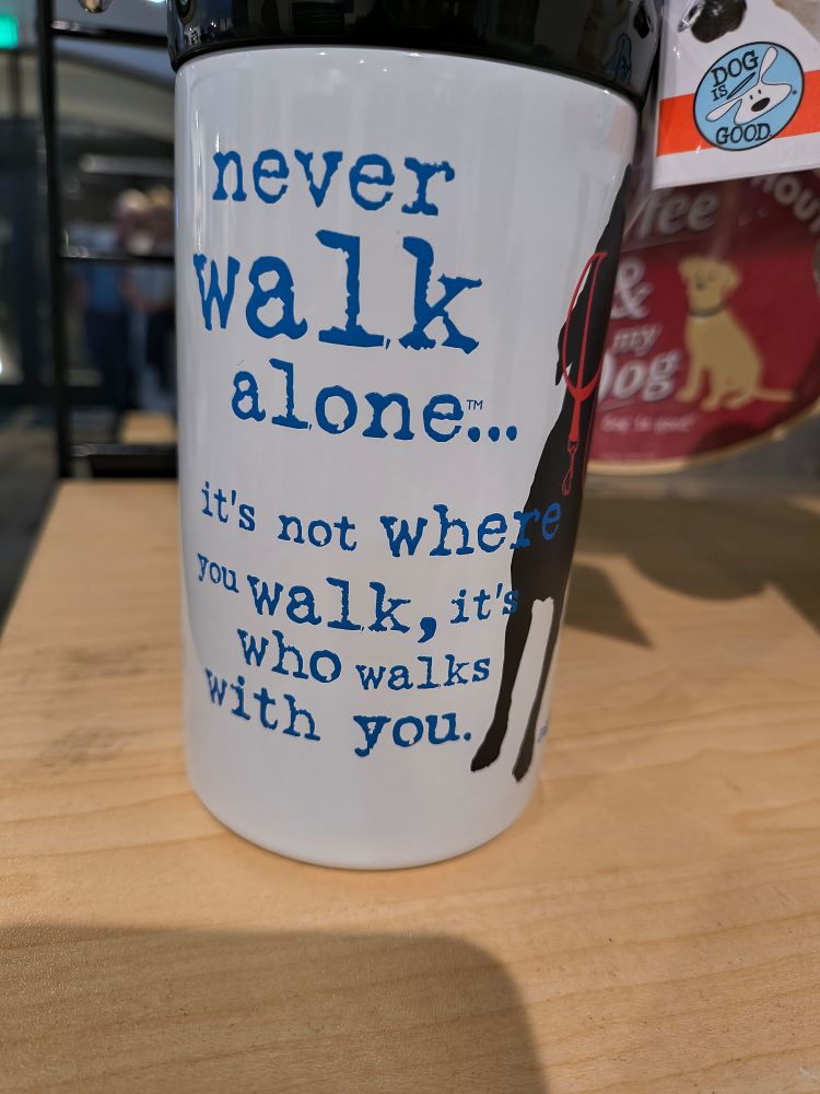 Cup with text that says "never walk alone... It's not where you walk, it's who walks with you."