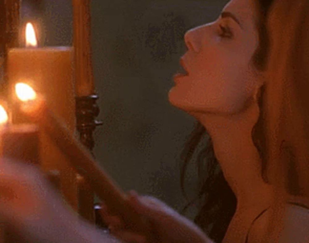 a woman is blowing out a candle in front of a bunch of lit candles