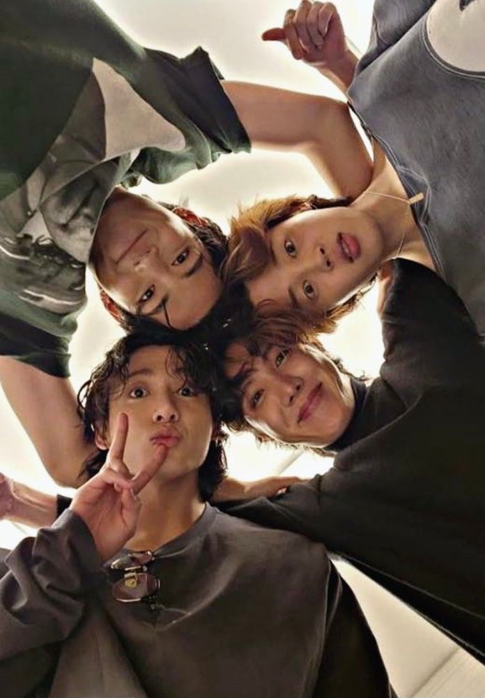 JHope, Jimin, V, and Jungkook of BTS are having a group hug and being cute for a photo with the camera on the floor and they're looking down
