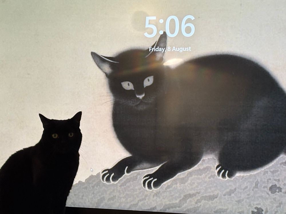 A black cat sits in front of a tv displaying a painting of a black cat.
