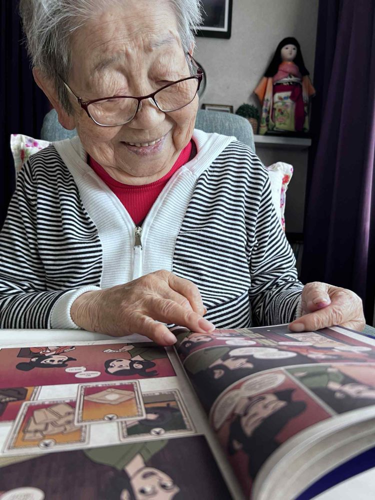My grandmother Taeko smiling while reading a copy of Folk Remedy book 1