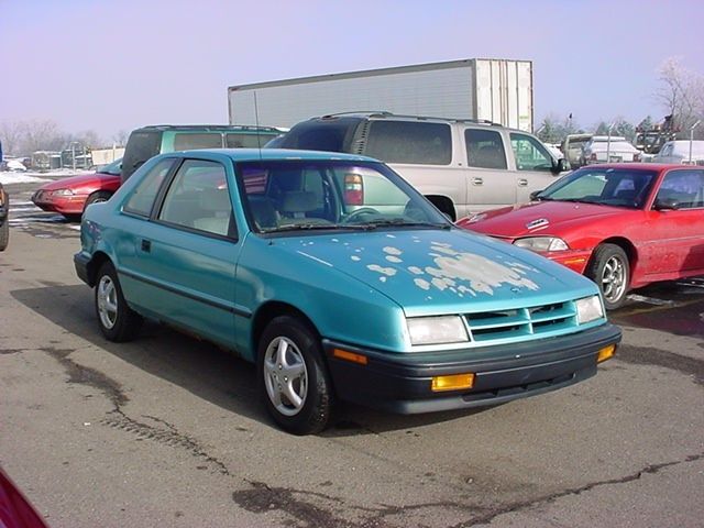 a turquoise dodge shadow 2-door. perhaps the finest car ever made. years of thrilling speed have stripped the hood of paint.