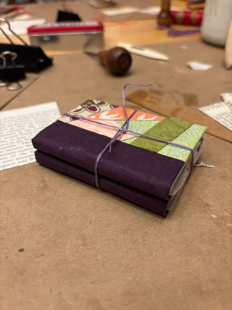 two mini hardcover quarter cloth books, tied together on a crafting table