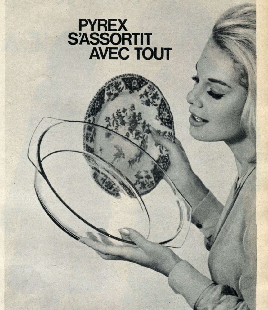 detail from a 1962 advert, a black and white photo of a woman in a white void holding a plate in her right hand and a casserole dish, which she's looking at, in her left hand, and it says Pyrex s'assortit avec tout